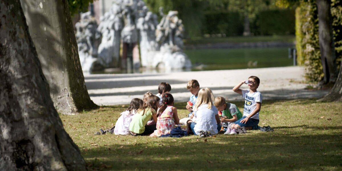 eine Gruppe von Kindern sitzt zusammen im Hofgarten in Würzburg und unterhalten sich