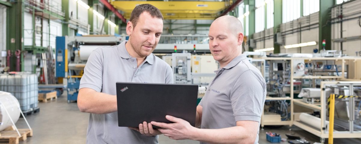 Zwei Mitarbeiter beim Arbeiten am Laptop in den Produktionshallen von Koenig und Bauer AG