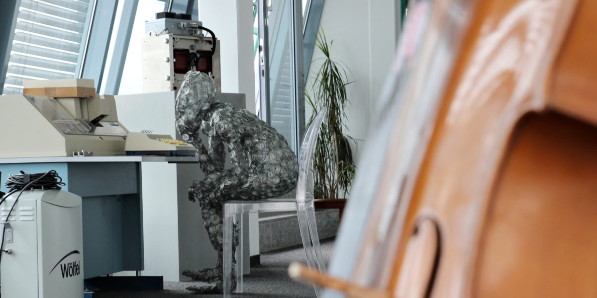 View through an office of a statue sitting in front of a computer thinking