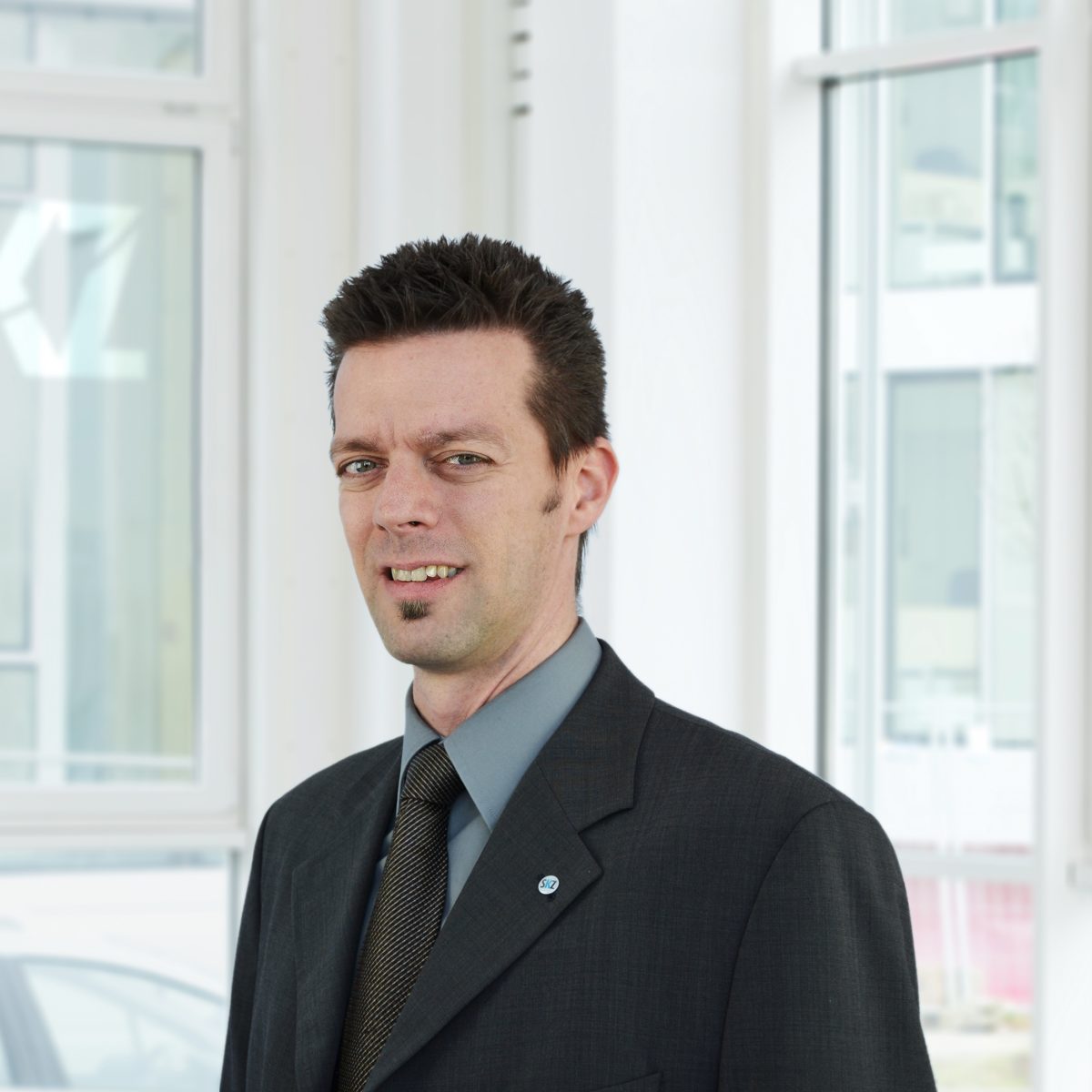 Portrait of smiling SKZ Kunststoff-Zentrum employee in black suit