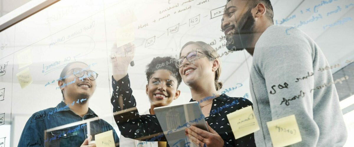 four people talking in front of a whiteboard and writing texts on it in Mainfranken