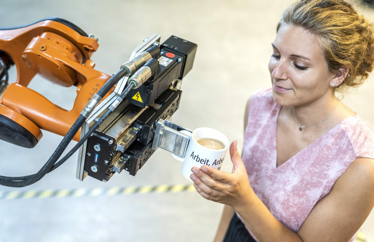 ein Roboterarm serviert einer Frau in rosa Top einen Tasse mit Kaffee